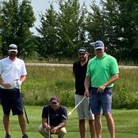 four alumni looking at golf ball